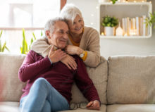 Happy senior couple embracing on a cozy couch, enjoying a warm and comfortable home environment.