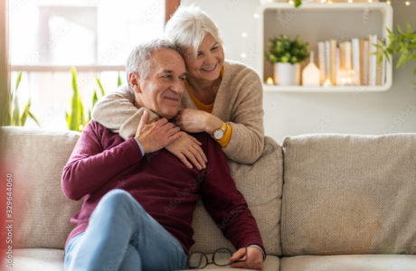 Happy senior couple embracing on a cozy couch, enjoying a warm and comfortable home environment.