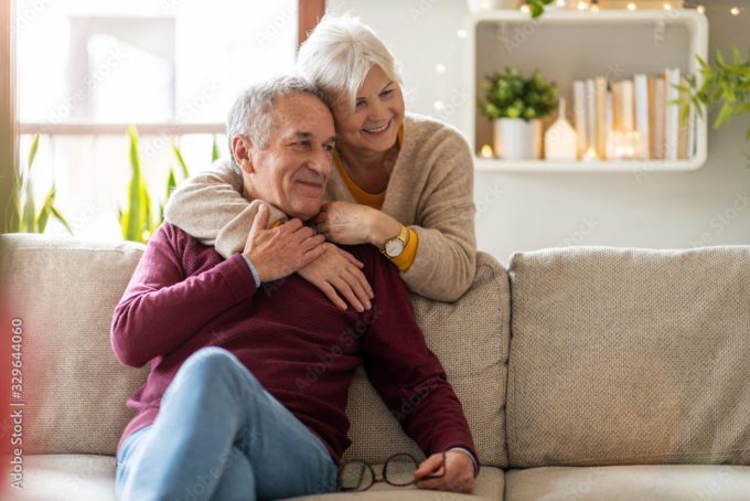 Happy senior couple embracing on a cozy couch, enjoying a warm and comfortable home environment.