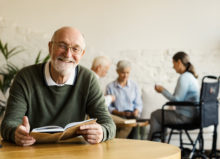 Senior man reading book and smiling in a senior community