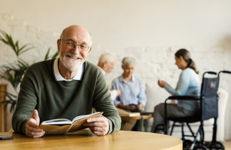 Senior man reading book and smiling in a senior community