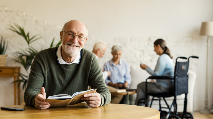 Senior man reading book and smiling in a senior community