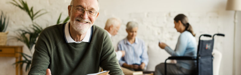 Senior man reading book and smiling in a senior community