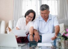 Senior couple at home doing taxes together seated on a couch