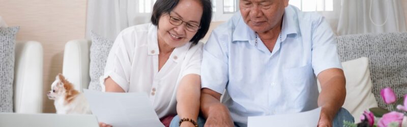 Senior couple at home doing taxes together seated on a couch